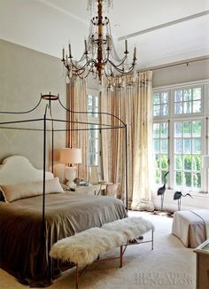 a bedroom with a bed, chandelier and windows