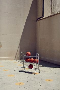 three basketballs are sitting on a rack in the middle of an empty parking lot