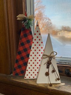 three wooden christmas trees sitting on top of a window sill