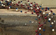 a branch with red, white and blue berries hanging from it's end on a wooden ledge