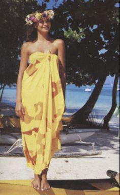 a woman in a yellow dress standing on the beach