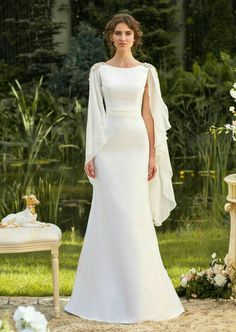 a woman in a white wedding dress standing next to a table with flowers on it