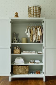 an organized closet with clothes and baskets on the shelves, including baby's clothing