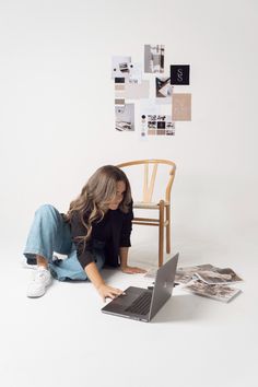 a woman is sitting on the floor with her laptop in front of her and papers scattered around her