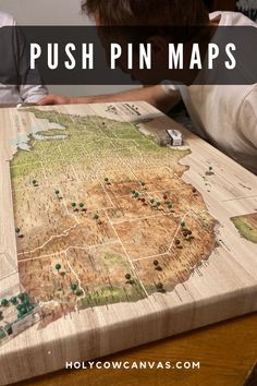 a person sitting at a table with a map on it that says push pin maps