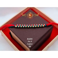 a red string bracelet sitting on top of a brown book in a wooden box with gold beads