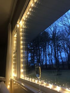 a glass of wine sitting on top of a window sill next to a tree