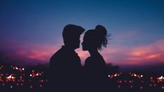 two people are standing in front of the sky at night with their faces close to each other