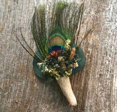 a green hat with feathers and flowers on top of a wooden table next to a tree