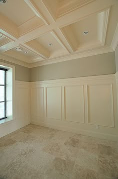 an empty room with white paneling and windows