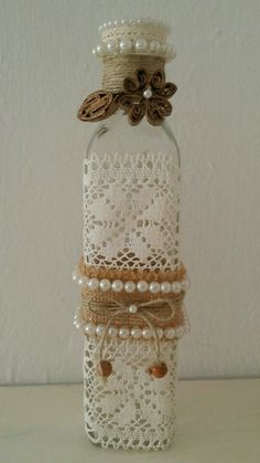 a glass bottle with lace and pearls on it