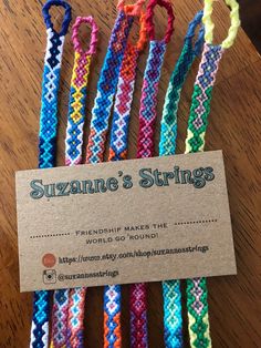 several different colored bracelets sitting on top of a wooden table next to a business card