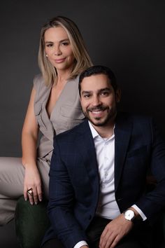 a man and woman sitting next to each other in front of a black background,