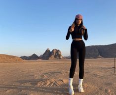 a woman standing in the middle of a desert