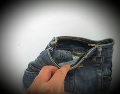 someone is holding their pocket open to reveal the inside of an empty pair of jeans