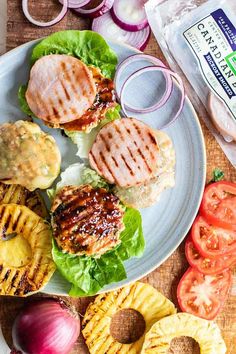 grilled chicken burgers with lettuce, tomatoes and onions on a plate