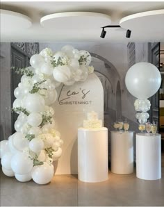 white balloons and cake on display in front of a wall