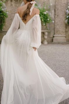 a woman in a white dress is walking down the street with her back to the camera