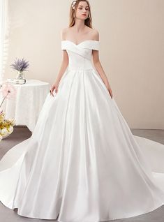 a woman in a white wedding dress standing next to a table with flowers on it