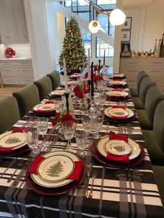 a dining room table set for christmas with place settings and holiday decorations on the table