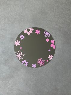 a black plate with pink and purple flowers painted on the side, sitting on a gray surface