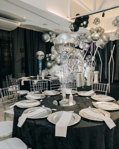 a black table with white plates and silver balloons