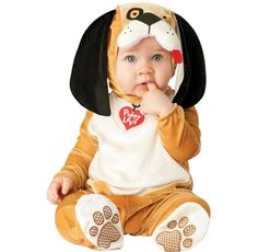 a baby in a dog costume sitting on the floor with his hand to his mouth