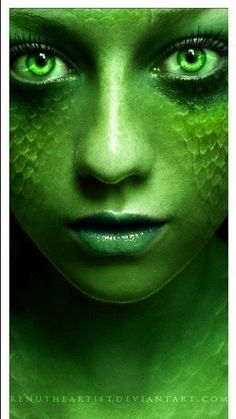 a woman with green eyes and makeup looks into the camera while she's surrounded by snakes