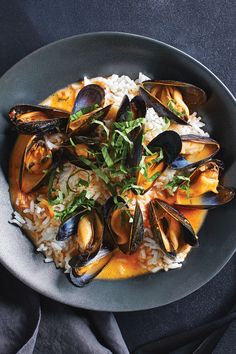 a plate with rice, mussels and sauce in it on a blue table cloth