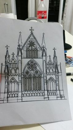 a drawing of a cathedral on a piece of paper in front of a coke bottle