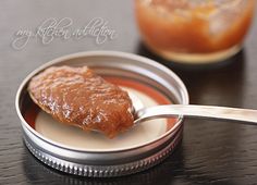 a spoon full of peanut butter on top of a table next to a jar of jelly