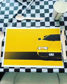 a yellow sports car on a black and white checkered table cloth with utensils