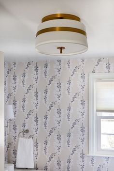 a bathroom with wallpaper and a light fixture