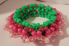 three bracelets with green and pink beads on a white surface, one in the shape of an elephant