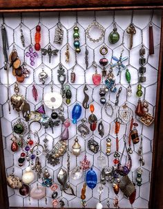 a wooden frame holding many different types of necklaces and earrings on it's sides