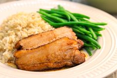 some meat and rice on a plate with green beans