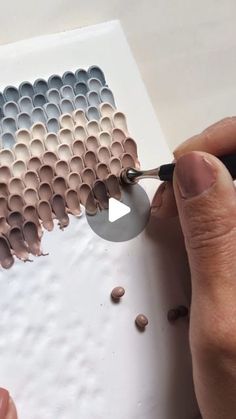 a person is using scissors to cut out paper circles on a piece of white paper