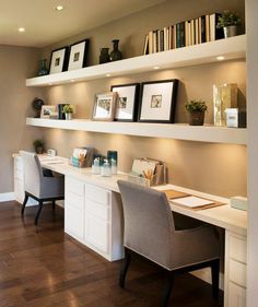 a home office with two desks and several bookshelves on the wall above them