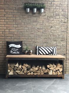 a wooden bench sitting next to a pile of firewood on top of a cement floor