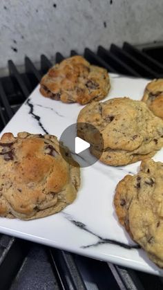 chocolate chip cookies sitting on top of a white plate next to an open oven door