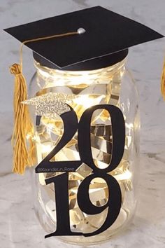 a graduation cap and tassel on top of a mason jar with lights in it