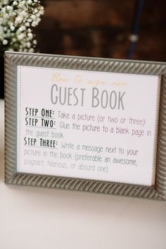 a guest book sign sitting on top of a table next to a vase filled with baby's breath flowers