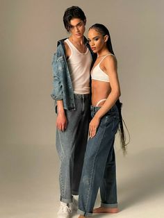 two people standing next to each other wearing jeans