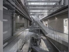 the inside of a building with stairs and railings leading up to two floors that have glass balconies on each floor