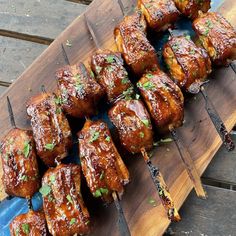 several skewered meats are sitting on a wooden board