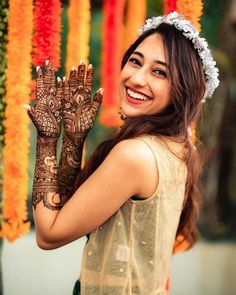 a woman is smiling and holding her hands up to show the henna on her hand