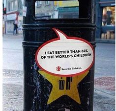 a black trash can with a speech bubble on it's side in front of a city street