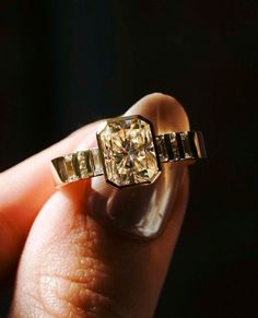 a person is holding an engagement ring with a yellow diamond in it's hand