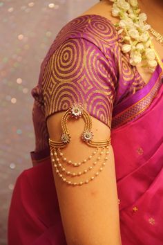 a woman in a pink sari with gold jewelry on her arm