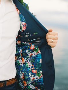 a man is holding his jacket open by the water